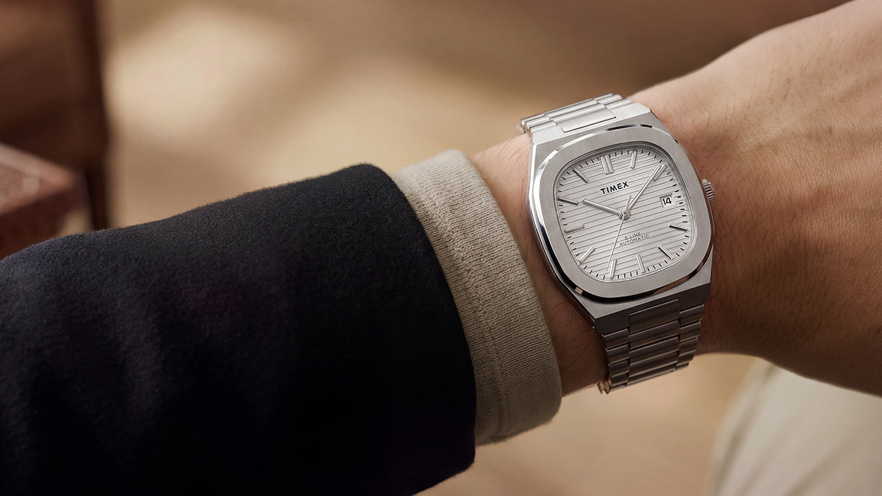 Close-up of the Timex® Automatic E Line 38mm stainless steel watch with a silver textured dial and date window worn on the wrist.