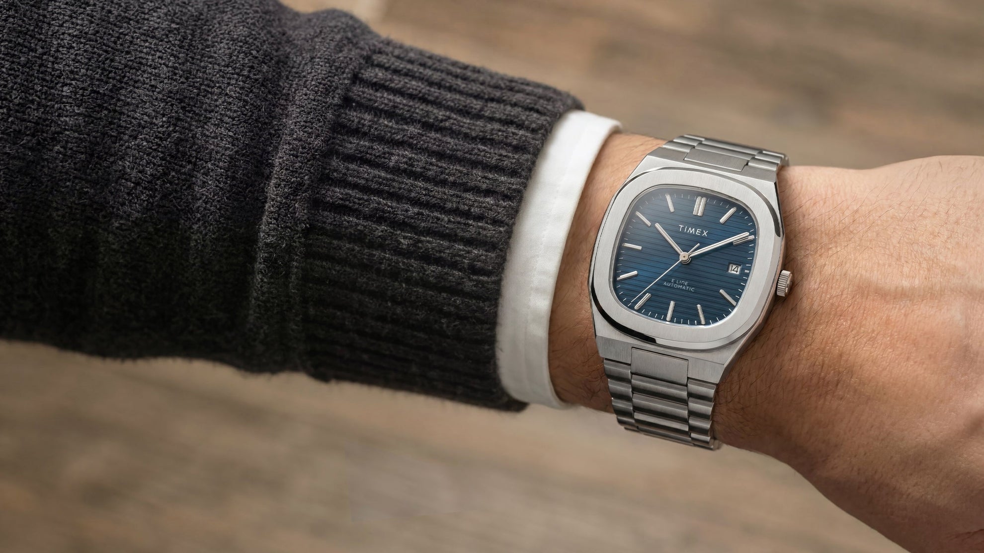Close-up of the Timex® Automatic E Line 38mm stainless steel watch with a blue textured dial and date window worn on the wrist.