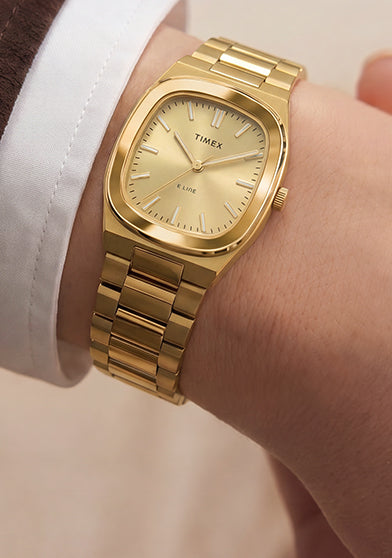 Close-up of the Timex® Quartz E Line 30mm gold-tone stainless steel watch with a champagne dial worn on the wrist.
