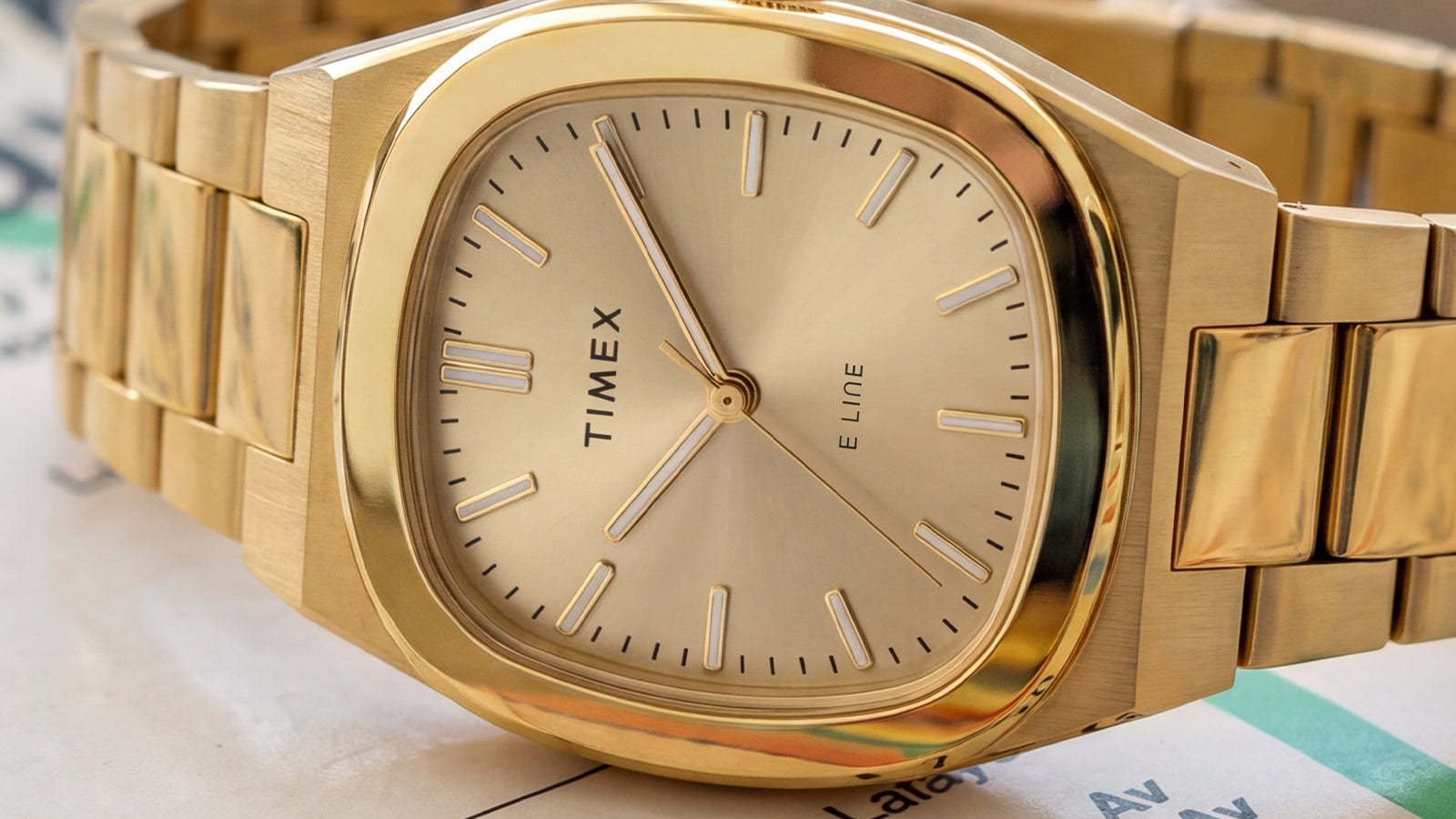 Close-up of the Timex® Quartz E Line 30mm featuring a champagne sunray dial, polished gold-tone case, and gold-tone stainless steel bracelet.
