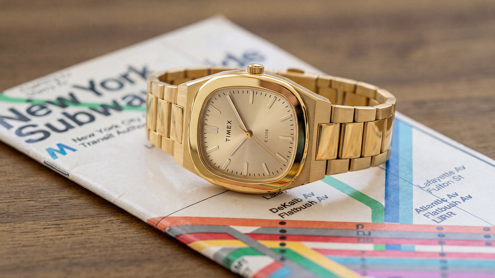 Close-up of the Timex® Quartz E Line 30mm gold-tone stainless steel watch displayed on a New York City subway map.