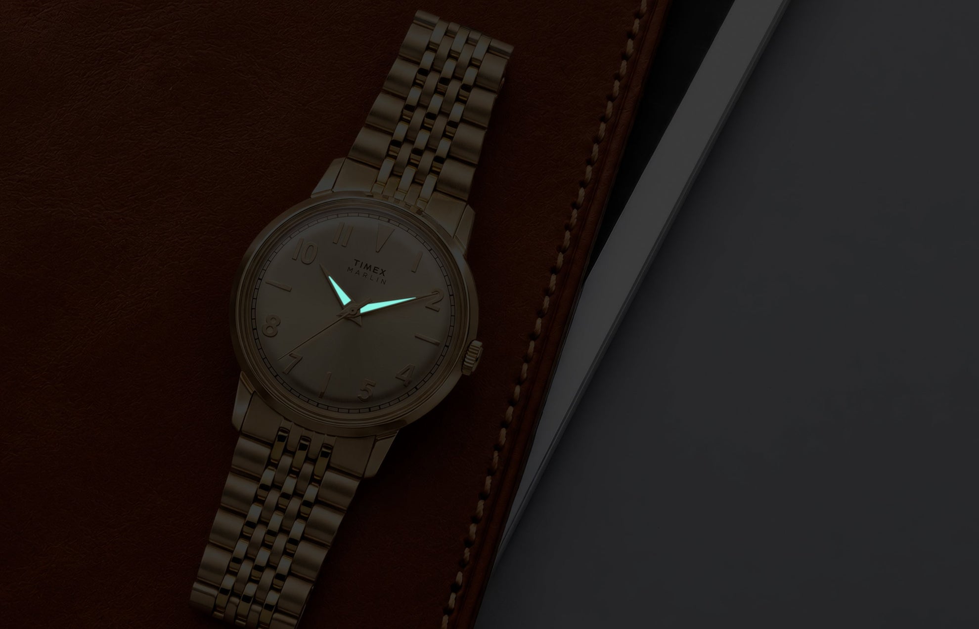 Timex Marlin Quartz watch with luminous hands glowing in low light against a champagne sunray dial.