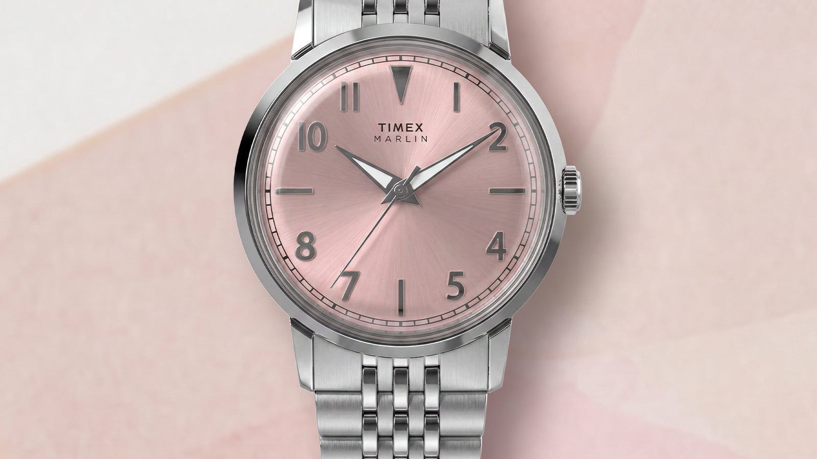 Close-up of the Timex Marlin Quartz featuring a pink sunray dial, applied silver-tone Arabic numerals, polished stainless steel case, and stainless steel bracelet.