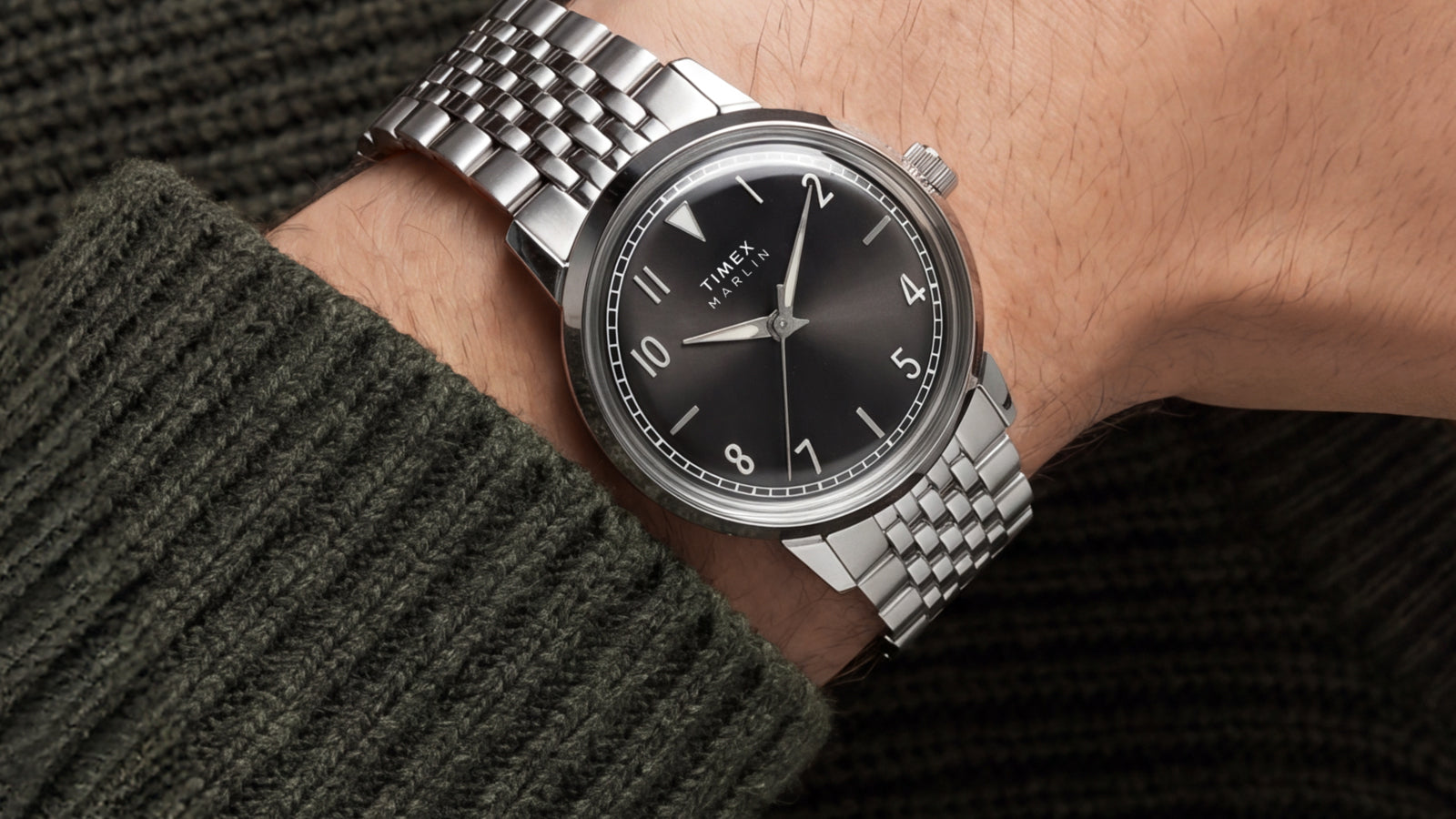 Close-up of the Timex Marlin Quartz with a black sunray dial and stainless steel bracelet worn on the wrist.