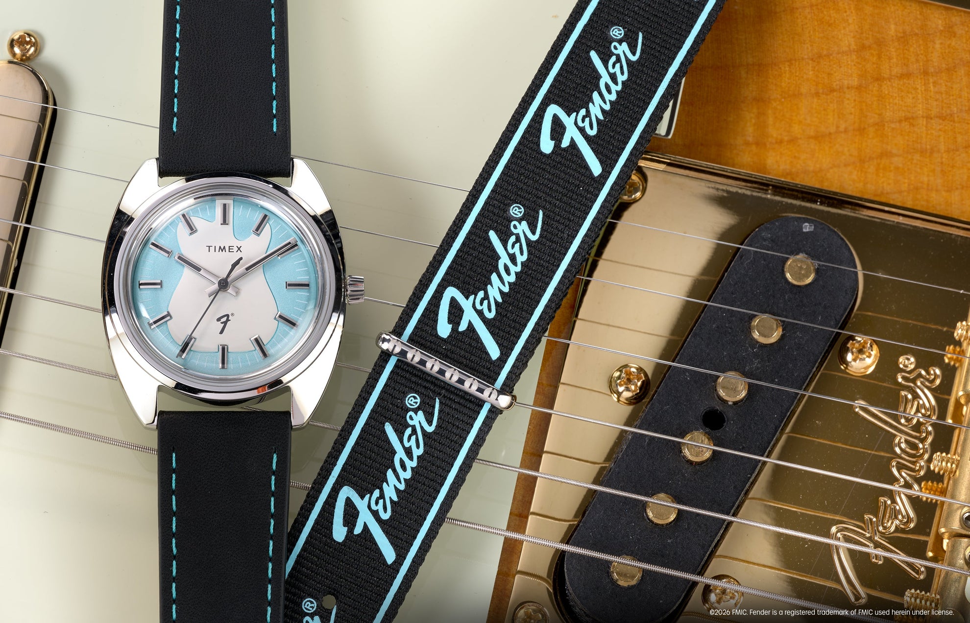 Fender x Timex watch with a silver-tone case, aqua-accented dial, and black strap displayed across a Fender electric guitar.