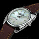 Angled close-up of the Fender x Timex watch highlighting its mother-of-pearl dial, brown leather strap, and tone-inspired crown.
