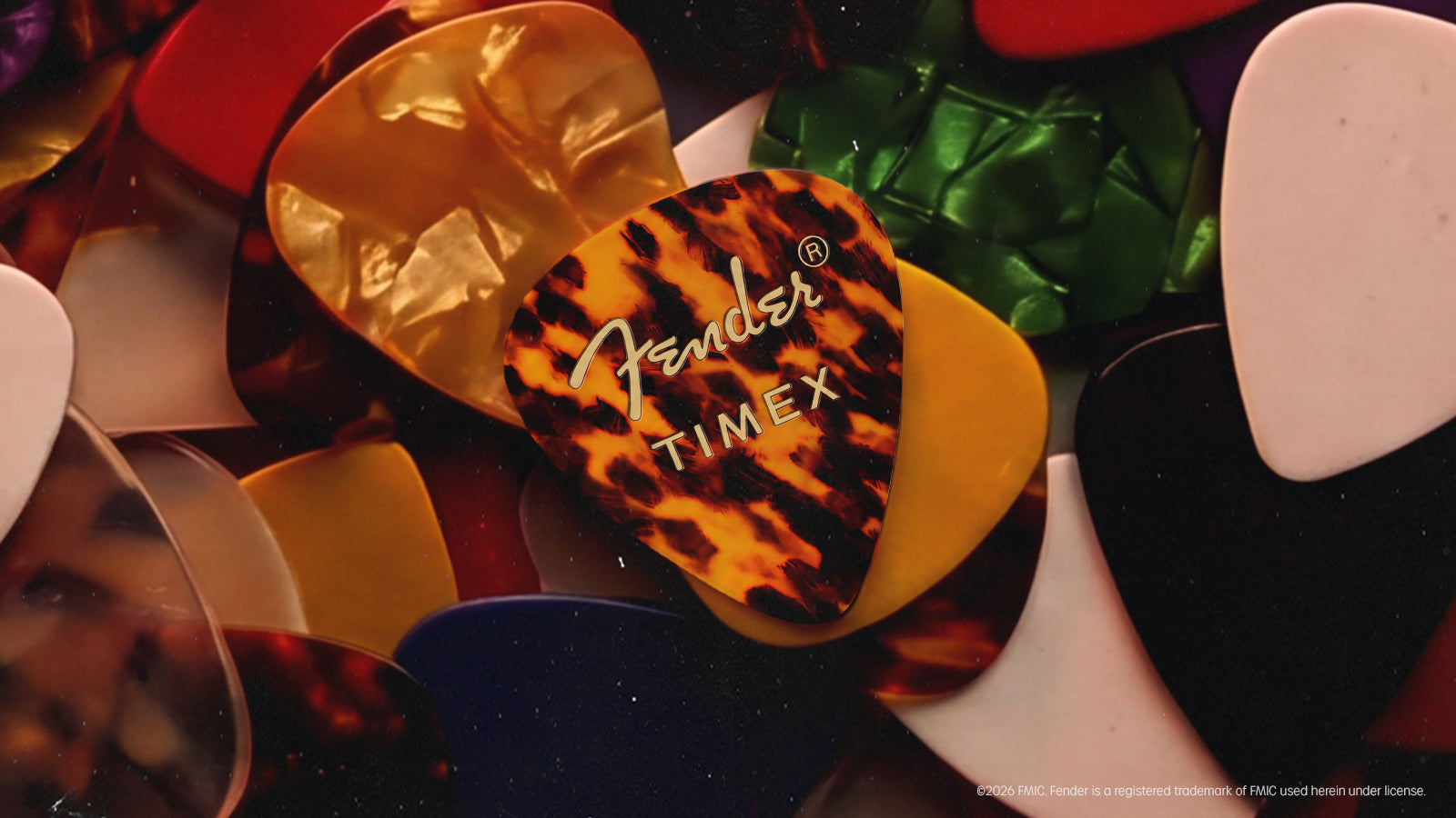 Fender x Timex tortoiseshell guitar pick displayed among colorful guitar picks.