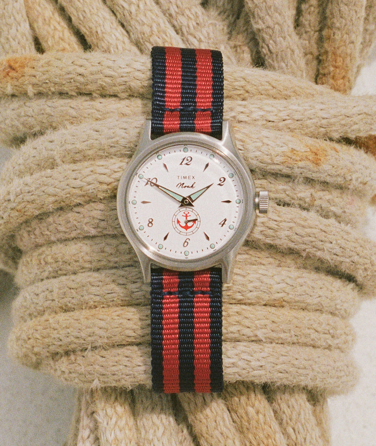 NOAH x Timex MK1 Anchor watch with a white dial and red-and-navy striped fabric strap resting on coiled nautical rope.