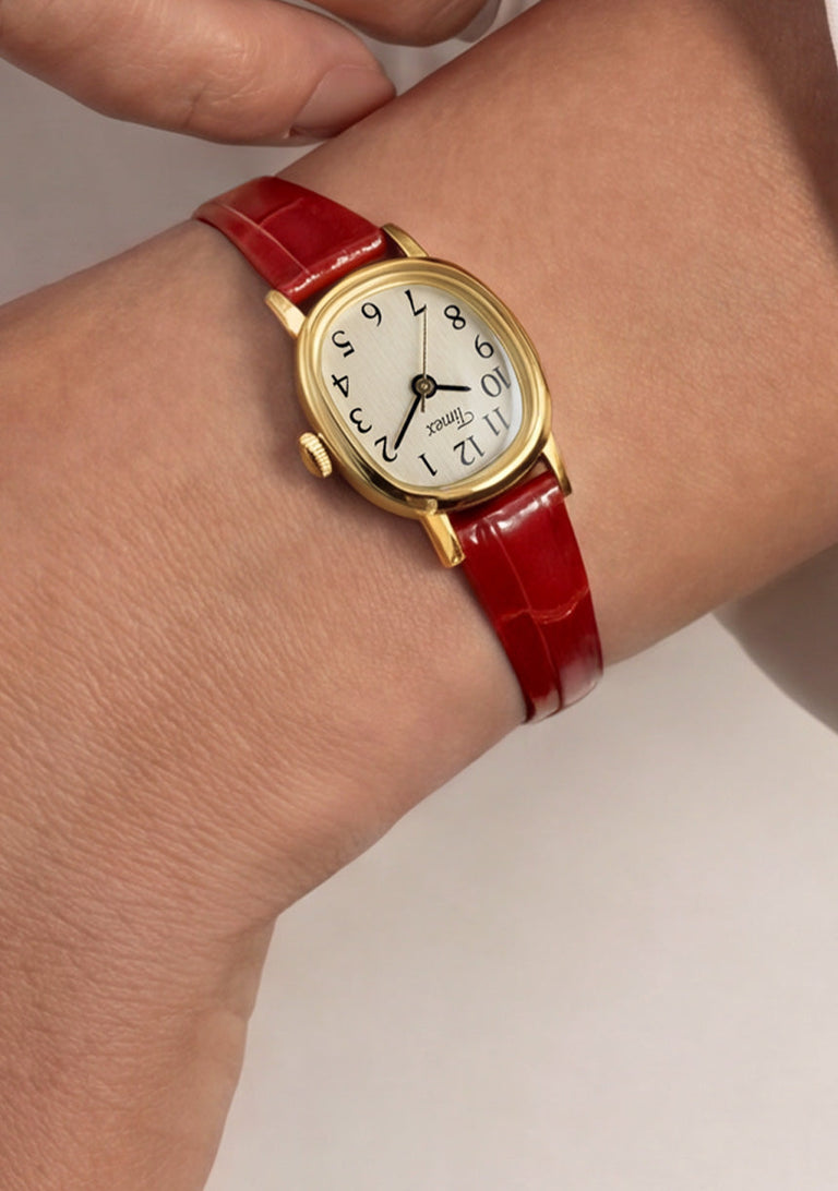 Cavatina® Mini watch with a gold-tone case and red leather strap worn on a wrist with a white outfit.