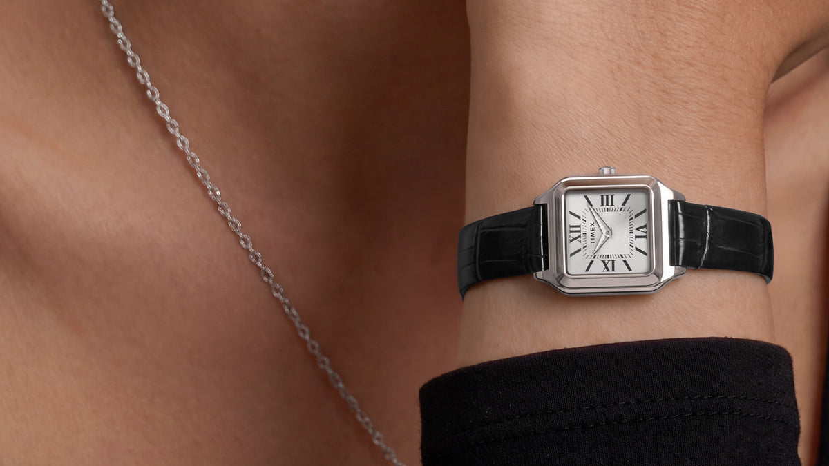 Timex Addison watch with a silver-tone rectangular case and black leather strap worn on the wrist.