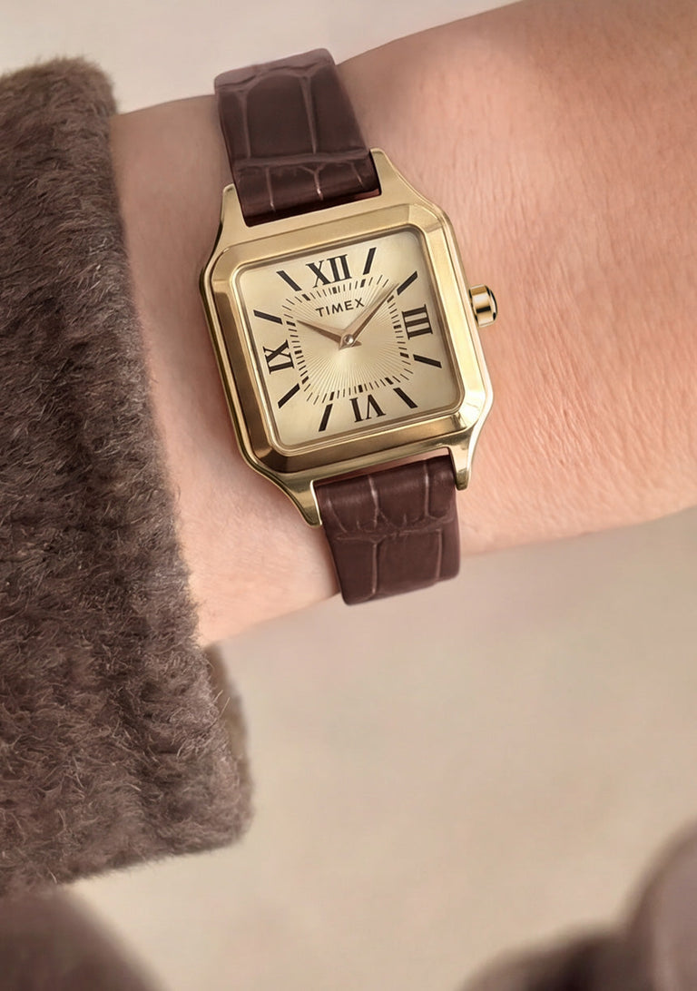 Timex Addison watch with a gold-tone case and brown croc-embossed leather strap worn on the wrist.