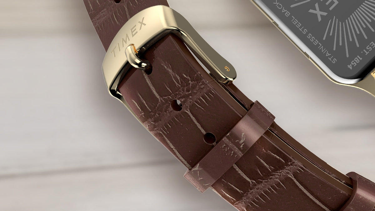 Close-up of the Addison watch’s brown croc-embossed leather strap and engraved gold-tone buckle.