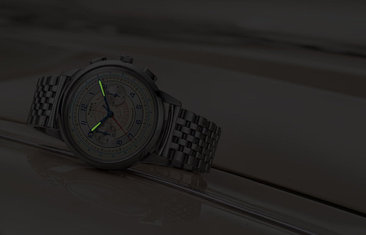 Marlin® Neo Classic Chronograph resting on a cream-colored car in low light with green luminous hands.