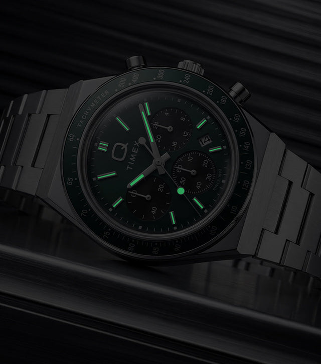 Q Timex Chronograph in low light, highlighting the glowing hands and hour markers.