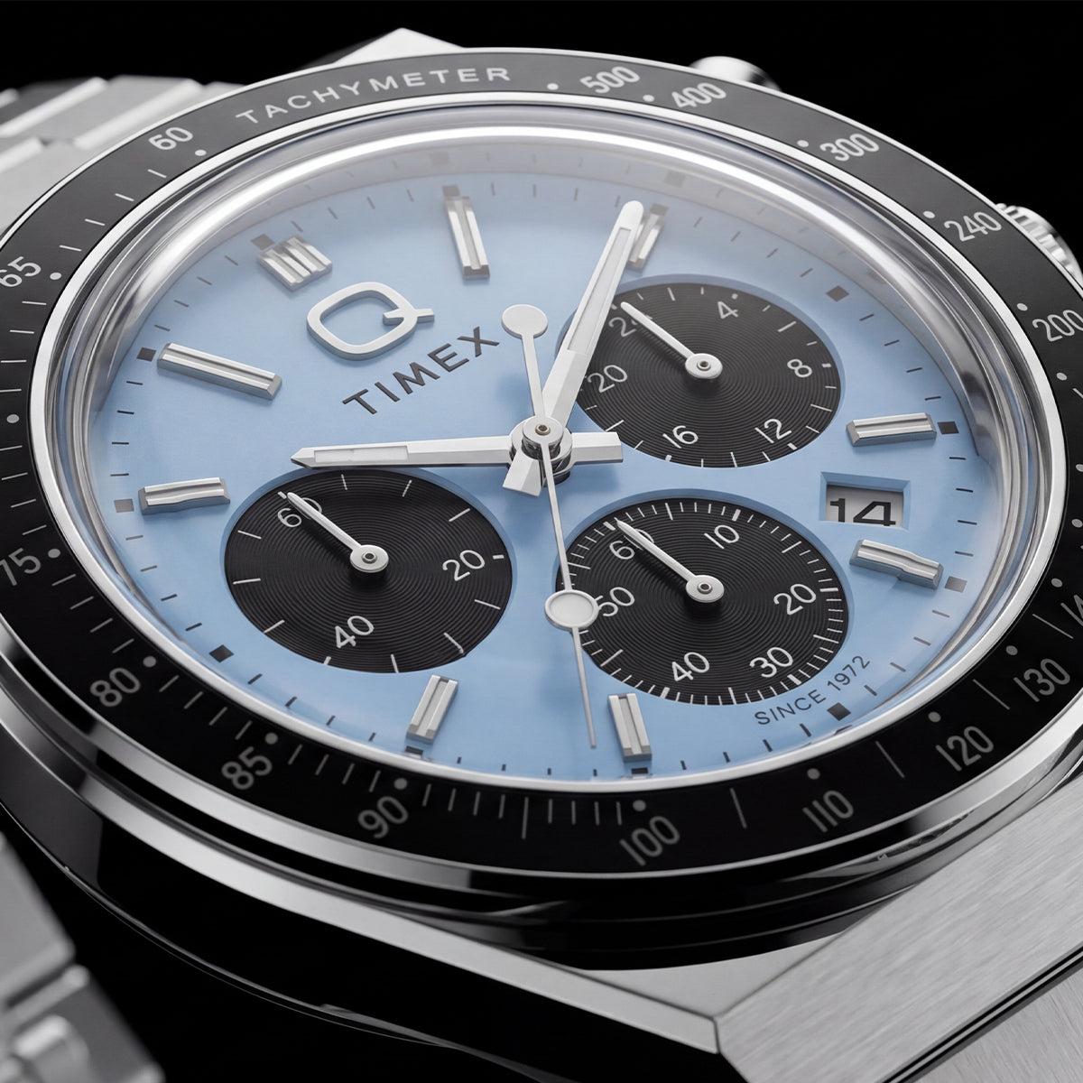 Close-up of the Q Timex Chronograph’s ice-blue dial, black subdials, date window, and tachymeter bezel.