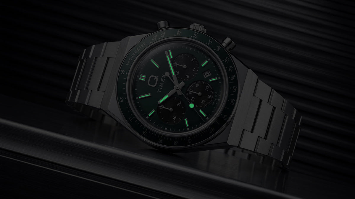 Q Timex Chronograph in darkness with illuminated hands and hour markers.