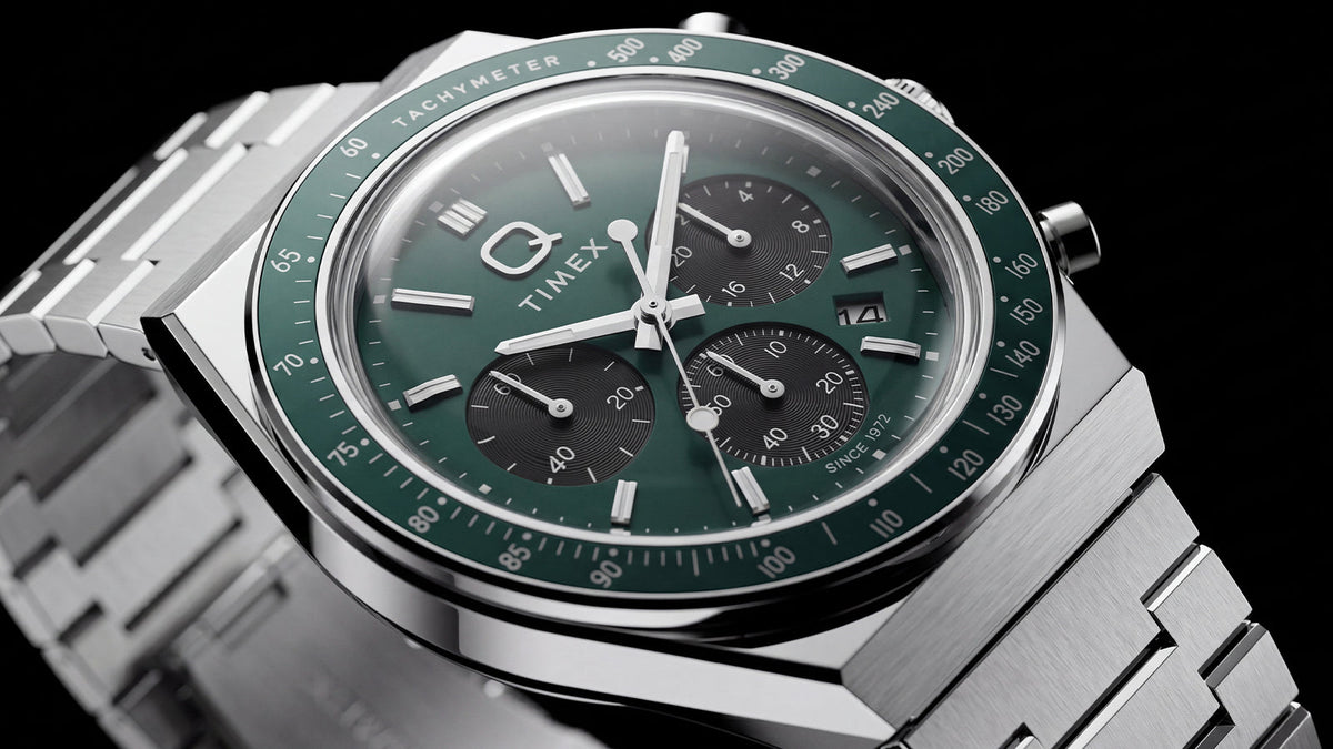 Detailed angled view of the Q Timex Chronograph’s green dial, black subdials, and stainless-steel case and bracelet.