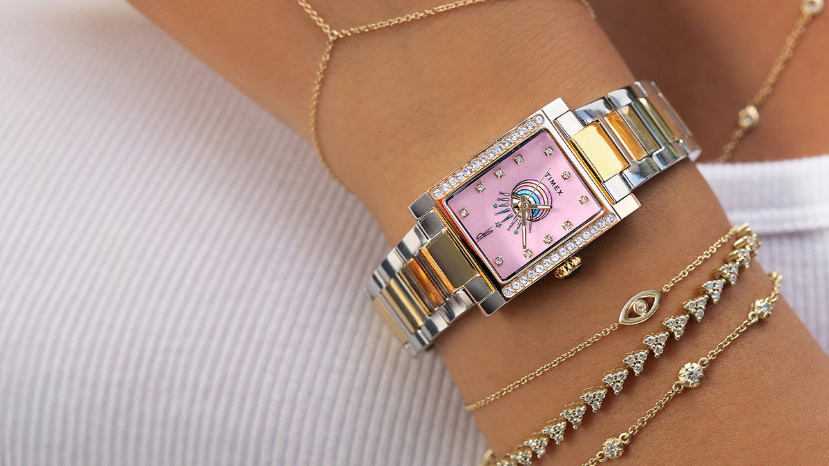 Timex x Jacquie Aiche Éclat two-tone watch worn alongside layered gold and diamond bracelets.