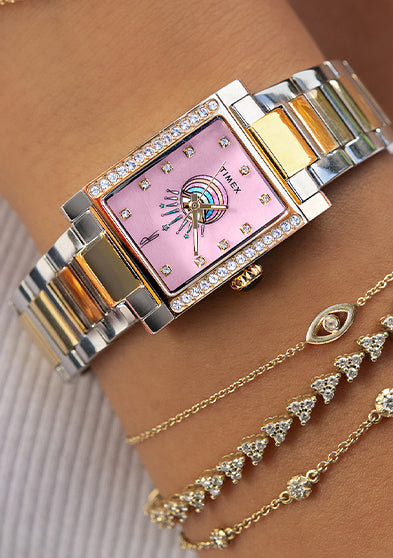 Timex x Jacquie Aiche Éclat two-tone watch worn alongside layered gold and diamond bracelets.