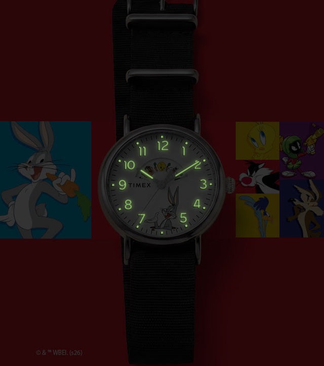 TW2Y99100 Looney Tunes Bugs and Friends x Timex Standard watch with glowing green hands and numerals beside Looney Tunes character artwork.