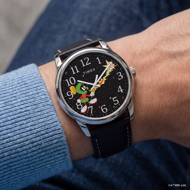 TW2Y99300 Marvin the Martian x Timex Easy Reader® watch worn on a wrist, featuring a black starry dial, silver-tone case, and black leather strap.