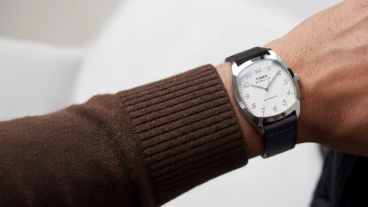 TW2Y84300 Marlin® Chatham Automatic watch worn with a brown knit sweater, featuring a white dial and black leather strap.