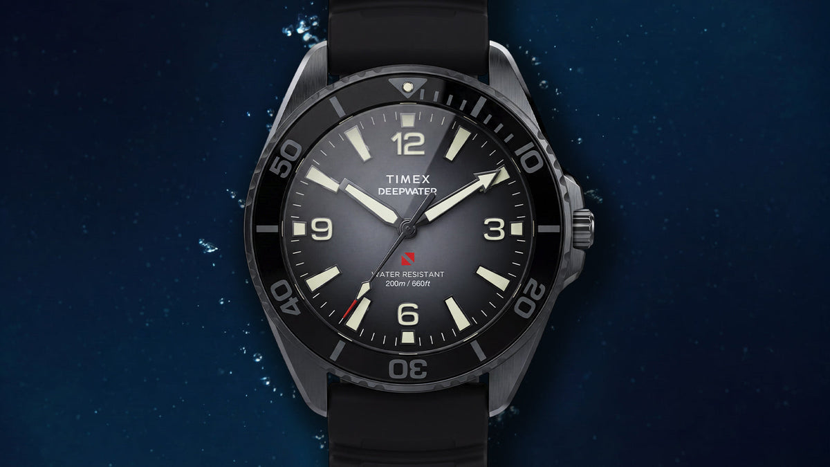 TW3A02000 Front view of the gray Deepwater Arctic 200 watch with a black bezel and strap against an underwater background.