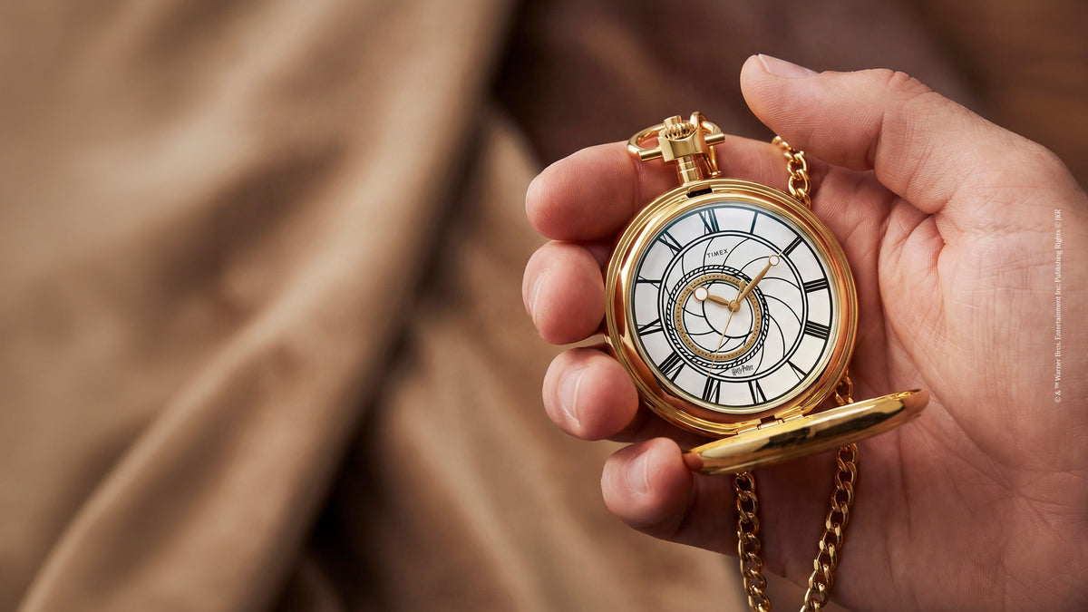 TW2Y99600 Hand holding the open pocket watch, with its Roman numeral dial and gold-tone chain visible.
