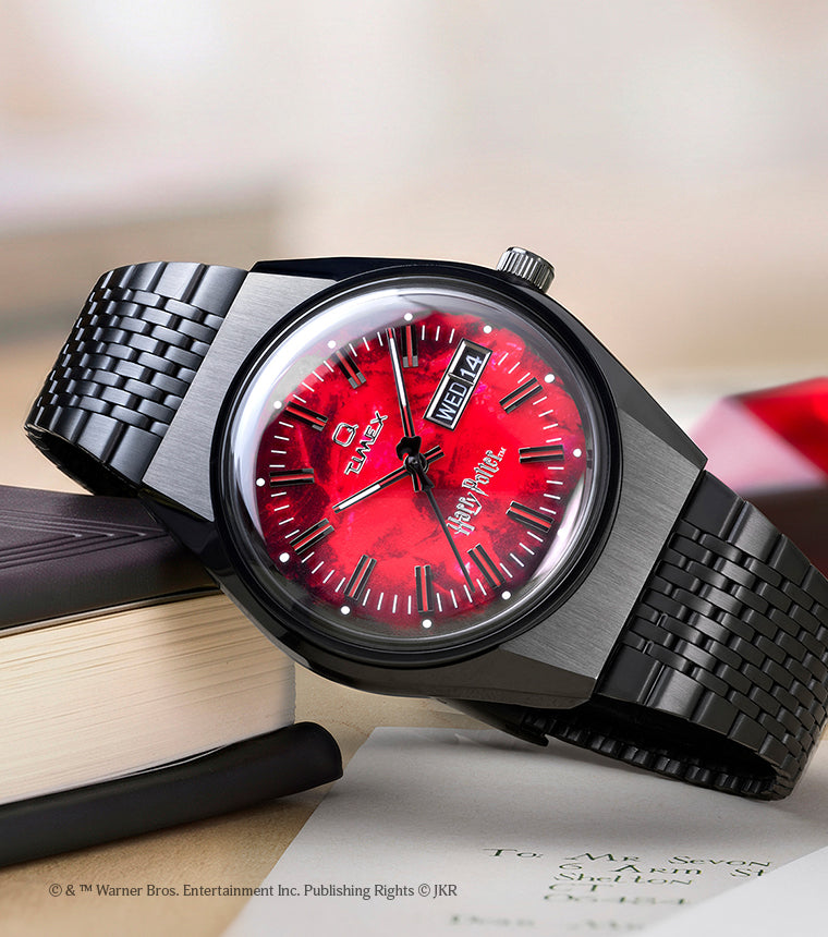 TW2Y99700 Harry Potter x Q Timex watch with a red Sorcerer’s Stone-inspired dial and black bracelet displayed beside books and a Hogwarts letter.