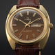 TW2Y87200 Close-up of the Timex 1978 Day Date Fumé Reissue’s brown gradient dial, gold-tone hands and hour markers, and day-date window.