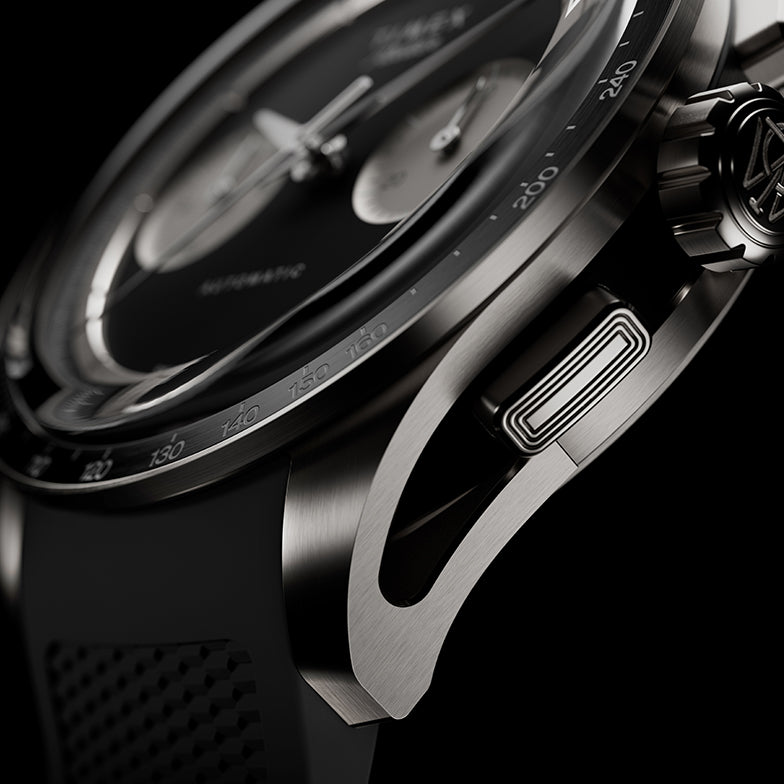 Detailed macro shot of the Timex Atelier Chronograph Automatic M1A Ti featuring a brushed titanium case, tachymeter bezel, signature crown, chronograph pusher, and precision-crafted lug design.