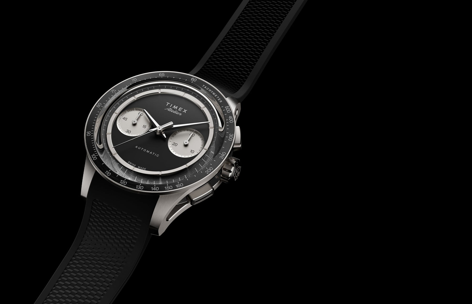 Timex Atelier Chronograph Automatic Ti M1a watch with black dial, titanium case, and textured black rubber strap on dark background
