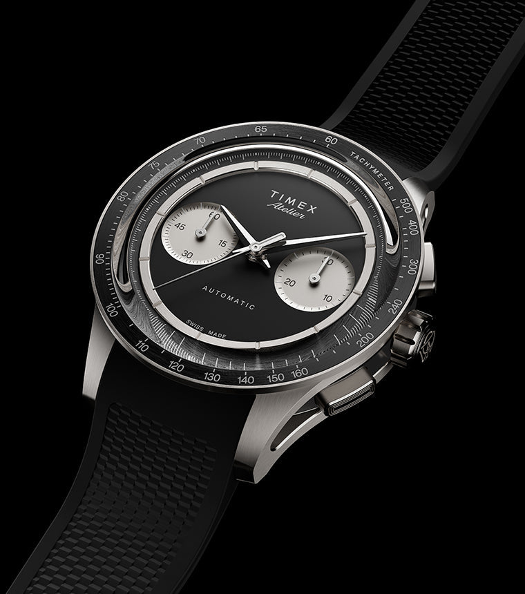 Timex Atelier Chronograph Automatic Ti M1a watch with black dial, titanium case, and textured black rubber strap on dark background