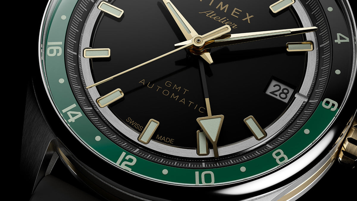 Detailed close-up of the GMT hand, date window, luminous markers, and green 24-hour scale.