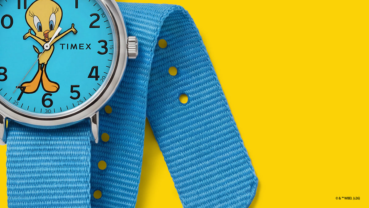 TW2Y99500 Close-up of the blue woven strap and adjustment holes beside the Tweety Bird x Timex Weekender character dial.