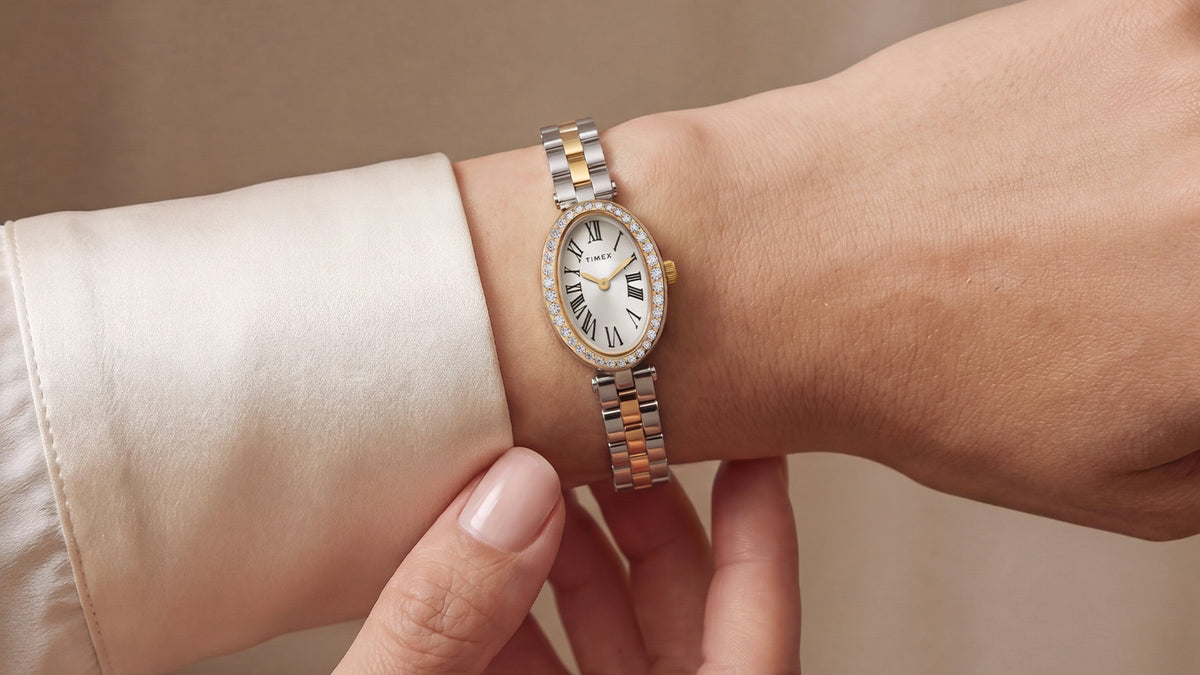 TW2Y90200 Timex Cavatina® Crystals watch worn on a wrist, showing its slim two-tone bracelet and crystal-lined case beside an ivory cuff.