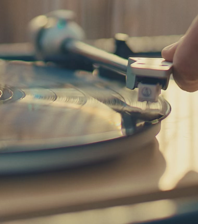 A warm holiday-themed montage featuring close-up shots of a spinning vinyl record, friends toasting drinks outdoors at dusk, and a detailed close-up of a Timex Waterbury chronograph watch glinting in soft light. The video ends with a nighttime sky and the message ‘Time is a Gift.’