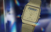 A close-up cinematic video of the Q Timex® 1982 Ana-Digi Reissue watch. The watch features a sleek stainless steel case and bracelet, with a dual analog-digital display. The analog hands move smoothly over the black dial, which includes a digital screen displaying time, date, and additional functions. The camera captures intricate details of the watch face, including the textured bezel and polished metal finish. The lighting shifts dynamically, emphasizing the craftsmanship and vintage-inspired design.