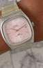 Timex Automatic 1983 E Line watch with a pink dial and stainless steel bracelet worn on the wrist.