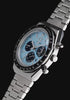 Rotating views of the ice-blue Q Timex Chronograph and its stainless-steel bracelet against a black background.