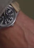 Person wearing and adjusting the MK1® Automatic watch with a black dial and tan fabric strap.