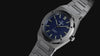 Timex Q Marbella stainless steel watch with a blue textured dial, featuring rotating product views, close-up details of the brushed bezel and dial, and a full front view highlighting its integrated bracelet and modern design.